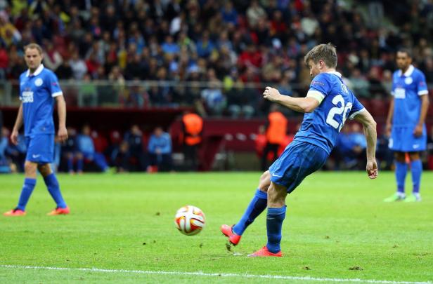 Ein Fußballspieler schießt den Ball auf einem grünen Rasen.
