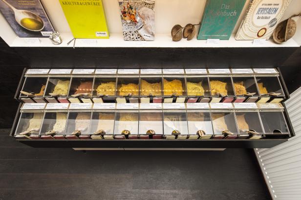 Ein Regal mit verschiedenen Currysorten und Kochbüchern in einem Geschäft.