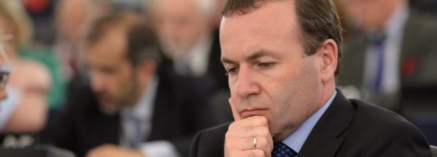 Ein Mann in einem Anzug sitzt nachdenklich da und stützt sein Kinn auf seine Hand.