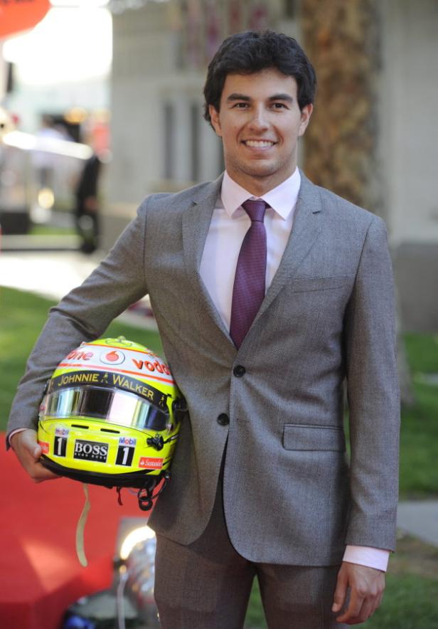 Sergio Pérez, ein Formel-1-Fahrer, hält einen Rennhelm in der Hand.