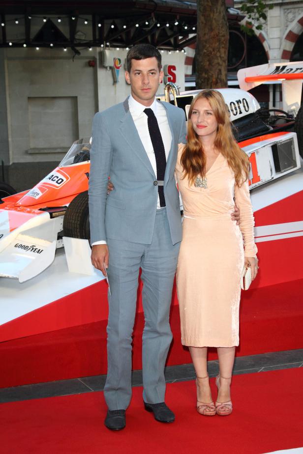 Mark Ronson und eine Frau posieren vor einem Formel-1-Rennwagen.