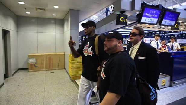 Dennis Rodman und Begleiter in einem Flughafenterminal.
