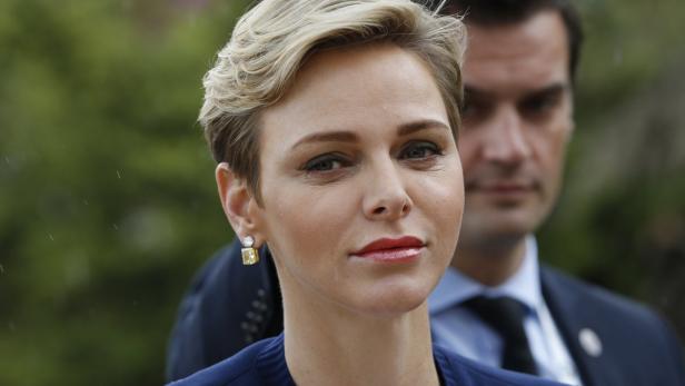 Fürstin Charlène von Monaco mit blonden, gewellten Haaren und gelben Ohrringen.