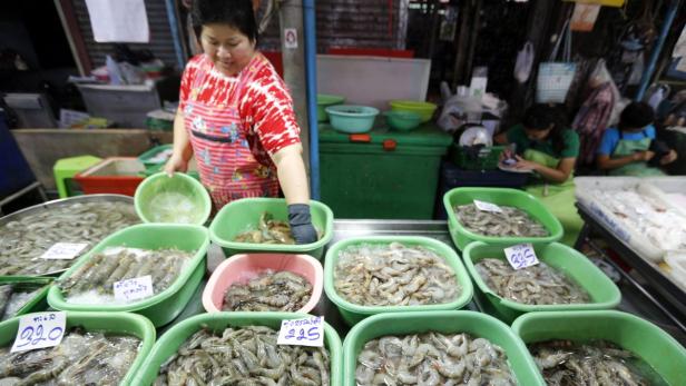 Eine Frau verkauft Garnelen auf einem Markt in Thailand.