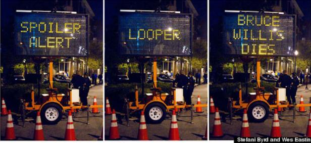 Drei Schilder zeigen Spoiler-Warnungen für den Film „Looper“, einschließlich des Todes von Bruce Willis.