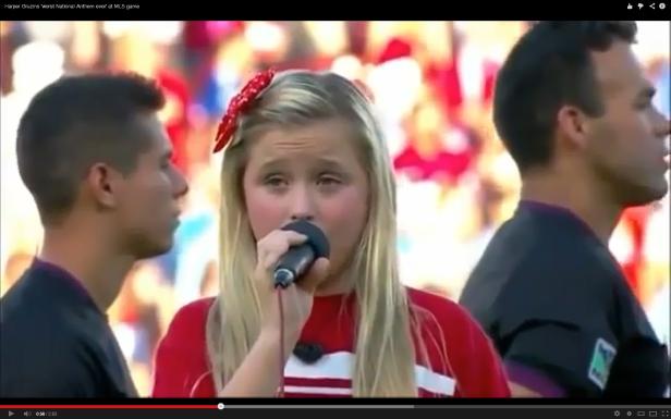 Ein junges Mädchen singt mit einem Mikrofon die Nationalhymne bei einem MLS-Spiel.