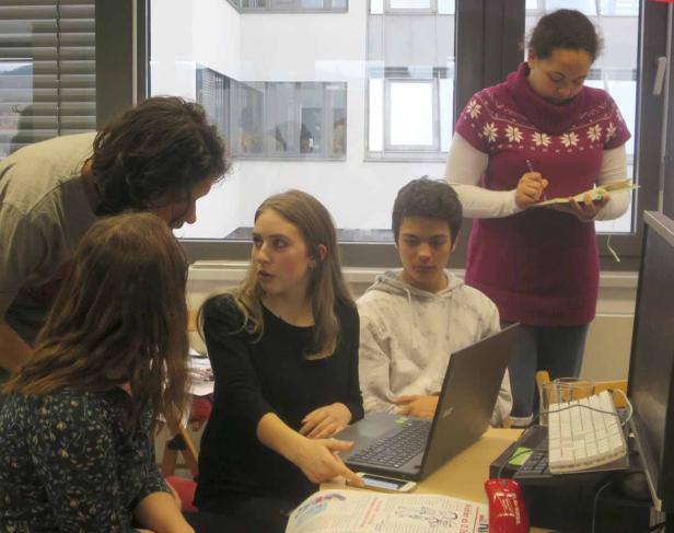 Eine Gruppe von Studenten arbeitet gemeinsam an einem Projekt mit Laptop und Notizen.