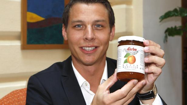 Martin Darbo: Hauptpreistreiber Zucker Ein Mann im Anzug präsentiert ein Glas „d’arbo Naturrein Rosen Marillen Konfitüre Extra“.
