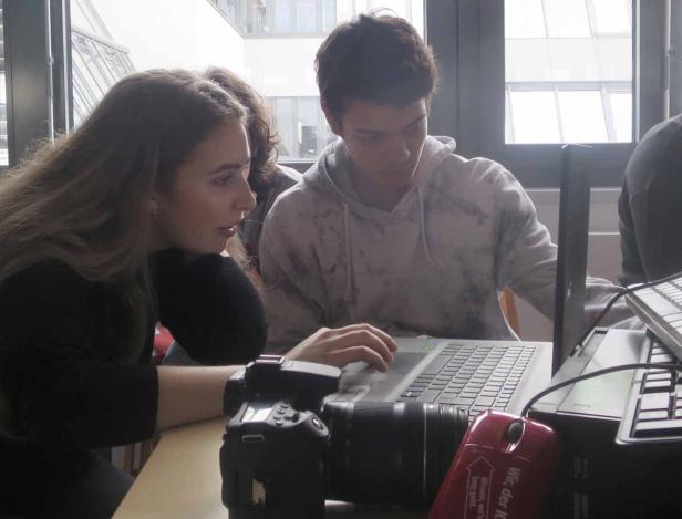 Eine junge Frau und ein junger Mann arbeiten gemeinsam an einem Laptop.