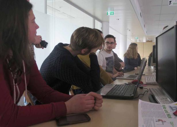 Mehrere Personen sitzen an einem Tisch mit Computern in einem Büro.