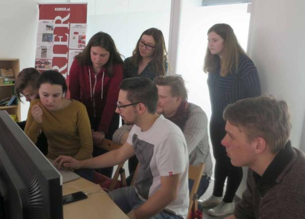 Eine Gruppe junger Leute schaut aufmerksam auf einen Computerbildschirm.