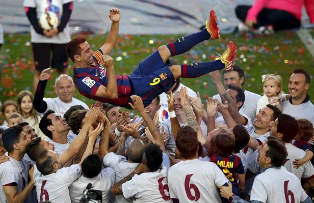 Fußballspieler Xavi wird von seinen Teamkollegen in die Luft geworfen.