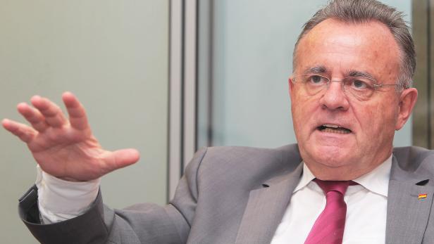 Ein Mann im Anzug gestikuliert mit der Hand.