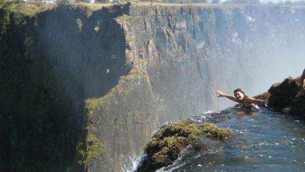 Eine Frau schwimmt im Devil's Pool an den Victoriafällen.