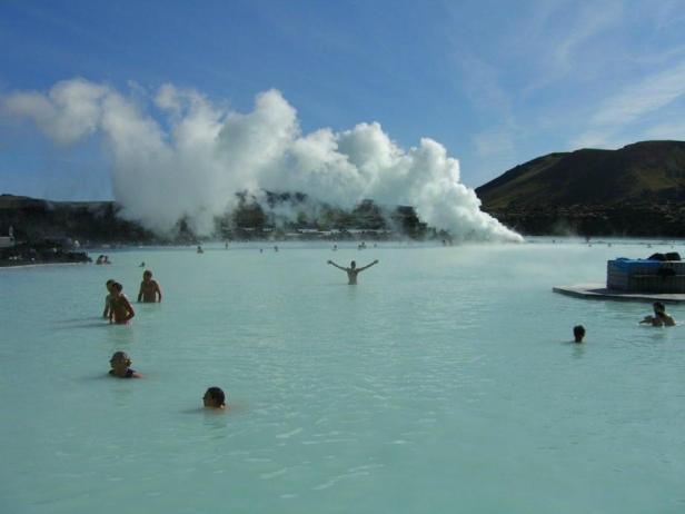 Menschen baden in der Blauen Lagune in Island, aus der Dampf aufsteigt.