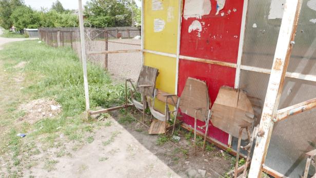 Eine heruntergekommene Bushaltestelle mit beschädigten Sitzen.