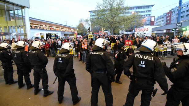 Polizisten stehen vor einer Menschenmenge bei einer Demonstration.