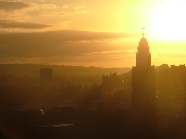 Ein Turm überragt eine Stadt im goldenen Licht der Abenddämmerung.