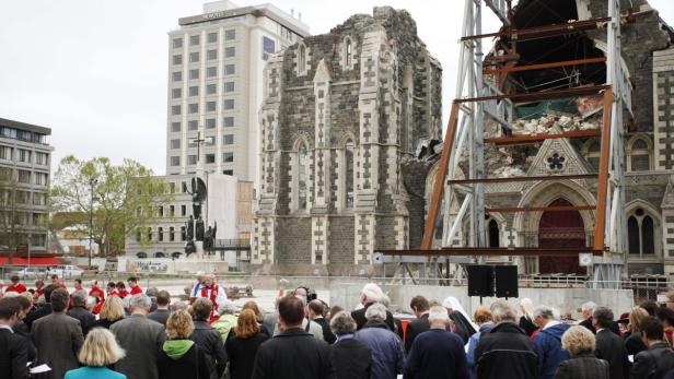 Eine Menschenmenge versammelt sich vor einer beschädigten Kathedrale in Christchurch, Neuseeland.