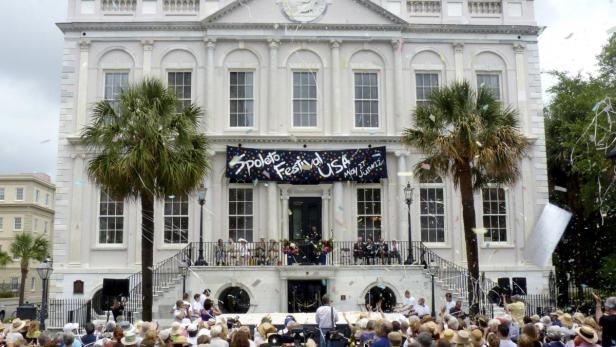 Das Spoleto Festival USA wird vor einem großen Gebäude mit Palmen gefeiert.