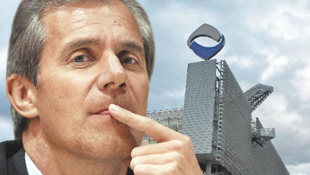 Ein Mann mit nachdenklichem Gesichtsausdruck vor einem Gebäude mit einem Logo.