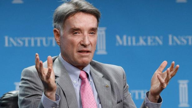 Ein Mann im Anzug gestikuliert vor dem Hintergrund des Milken Institute.