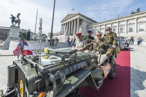 Militärfahrzeug mit vier Personen in Uniform vor dem österreichischen Parlament.