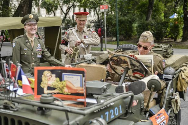 Drei Männer in Militäruniformen posieren in einem olivgrünen Jeep mit verschiedenen Accessoires.