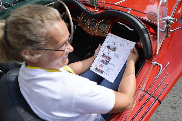 Eine Frau liest Anweisungen für die Vienna Classic Days 2014 in einem roten Oldtimer.
