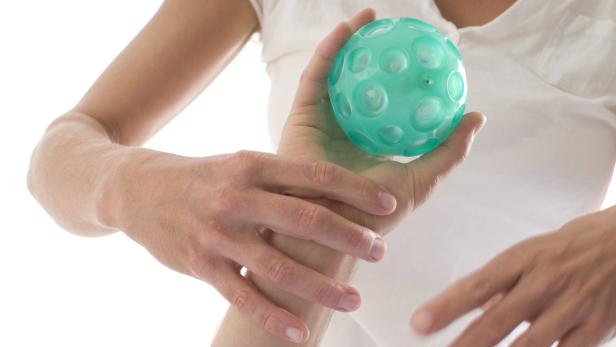 Eine Frau hält einen türkisfarbenen Noppenball in der Hand.