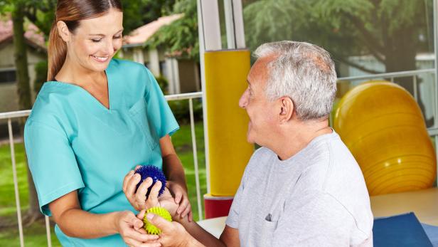 Eine Physiotherapeutin behandelt einen älteren Mann mit Igelbällen.