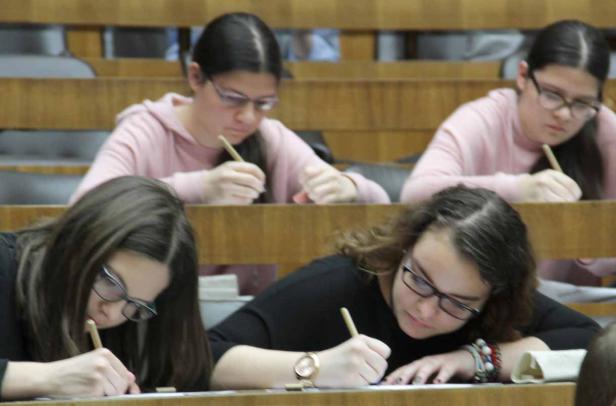 Mehrere Studentinnen sitzen in einem Hörsaal und schreiben eine Klausur.