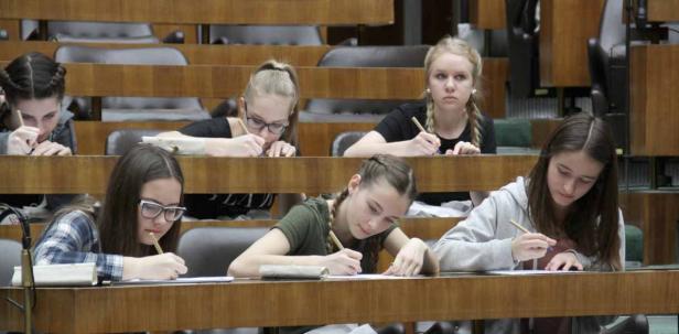 Mehrere Schülerinnen sitzen in einem Klassenzimmer und schreiben an ihren Tischen.