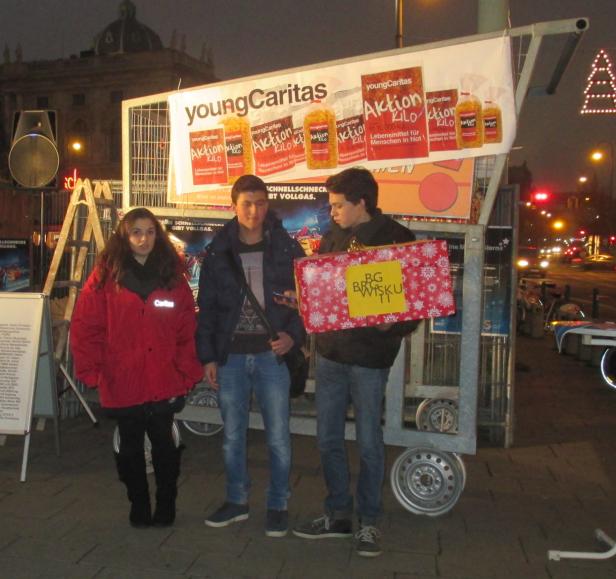 Drei Jugendliche stehen vor einem Stand der Young Caritas mit einer Geschenkbox.