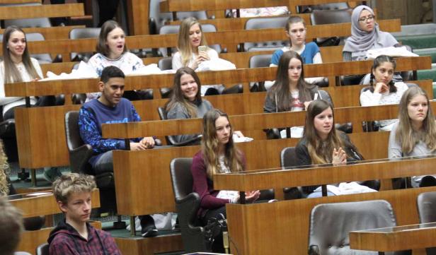 Eine Gruppe von Jugendlichen sitzt in einem Auditorium oder Parlament.