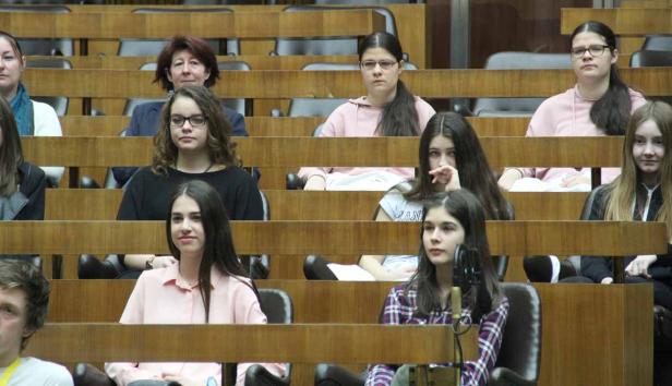 Eine Gruppe junger Menschen sitzt in einem Auditorium oder Gerichtssaal.