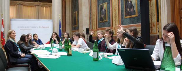 Jugendliche sitzen an einem Tisch im österreichischen Parlament und diskutieren.