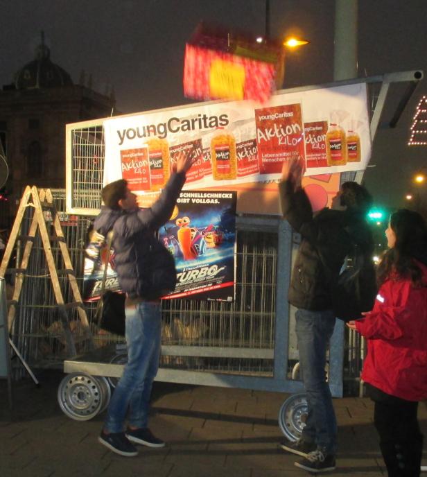 Junge Leute werfen Pakete in einen Einkaufswagen der „Young Caritas“-Aktion.