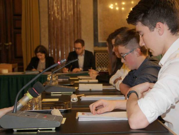 Mehrere Personen sitzen an einem Tisch während einer Konferenz.