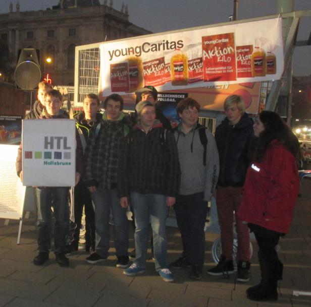 Eine Gruppe Jugendlicher steht vor einem Stand der „Young Caritas Aktion Kilo“.