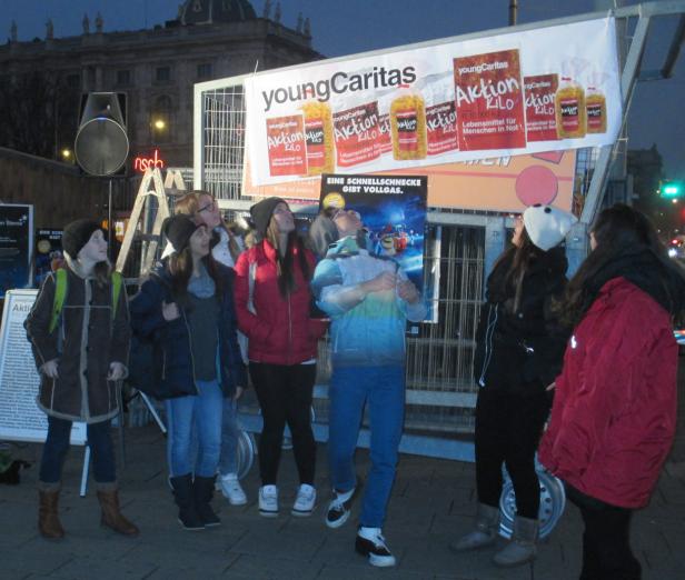 Eine Gruppe junger Leute steht vor einem Stand der „Young Caritas Aktion Kilo“.