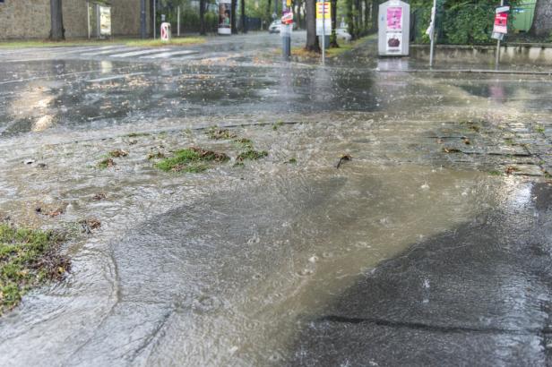 Starker Regen führt zu Überschwemmungen auf einer Straße.