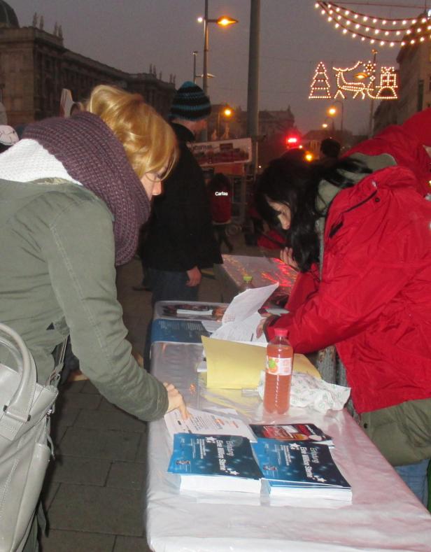 Zwei Frauen stehen an einem Tisch mit Flyern und Informationsmaterialien.