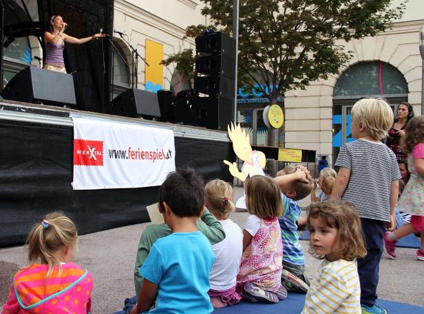 Eine Sängerin tritt auf einer Bühne vor einer Gruppe von Kindern auf.
