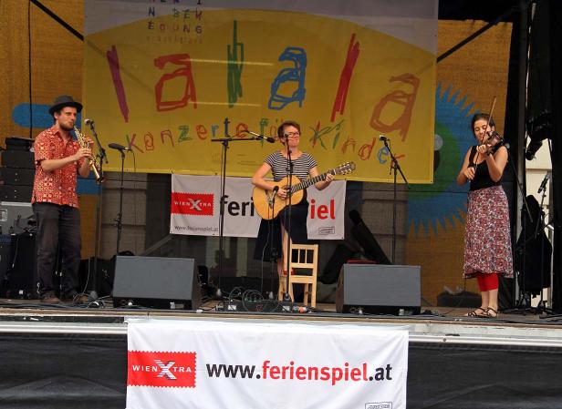 Eine Musikgruppe spielt auf einer Bühne mit dem Schriftzug „Ferienspiel“.