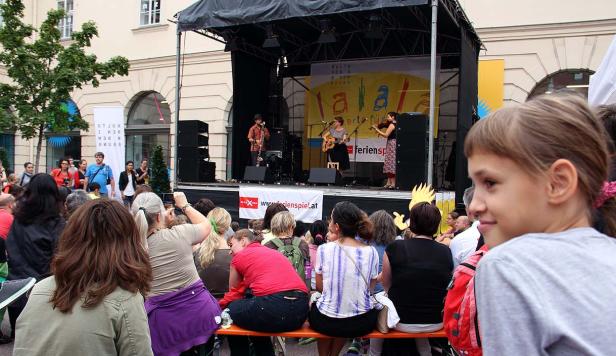 Eine Band spielt auf einer Bühne vor einem Publikum im Freien.