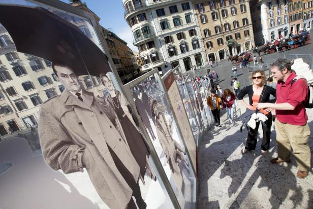 Eine Ausstellung mit Modefotografien in Rom, im Hintergrund eine belebte Piazza.
