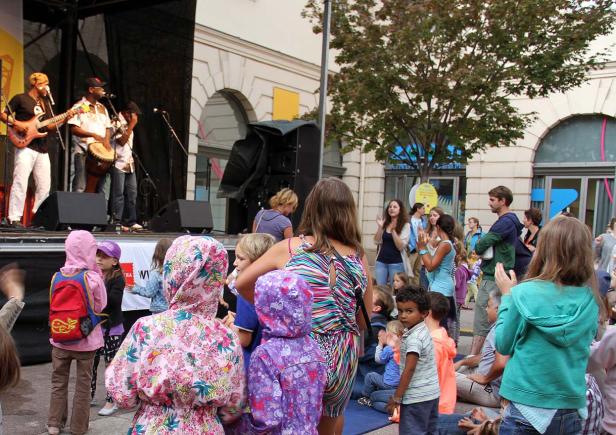 Eine Band spielt auf einer Bühne vor einem Publikum aus Kindern und Erwachsenen.
