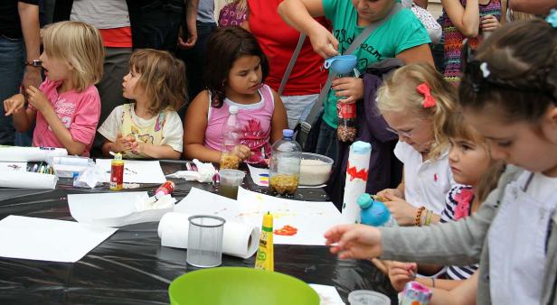 Mehrere Kinder sitzen an einem Tisch und basteln mit verschiedenen Materialien.