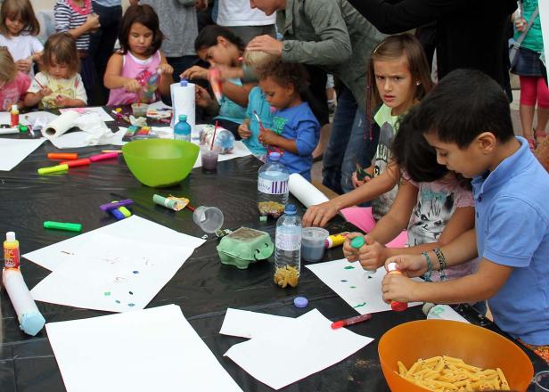 Kinder basteln und malen an einem Tisch im Freien.